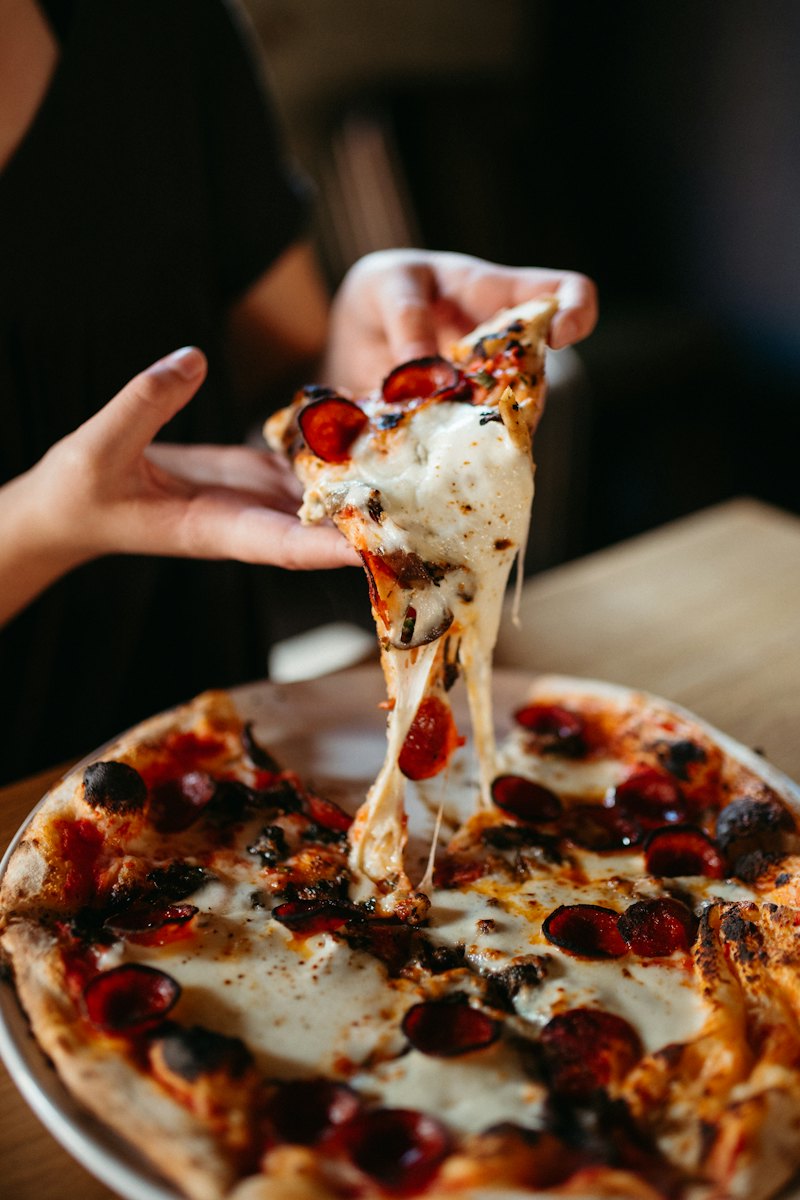 Una fetta di pizza al salamino piccante, con la mozzarella filante